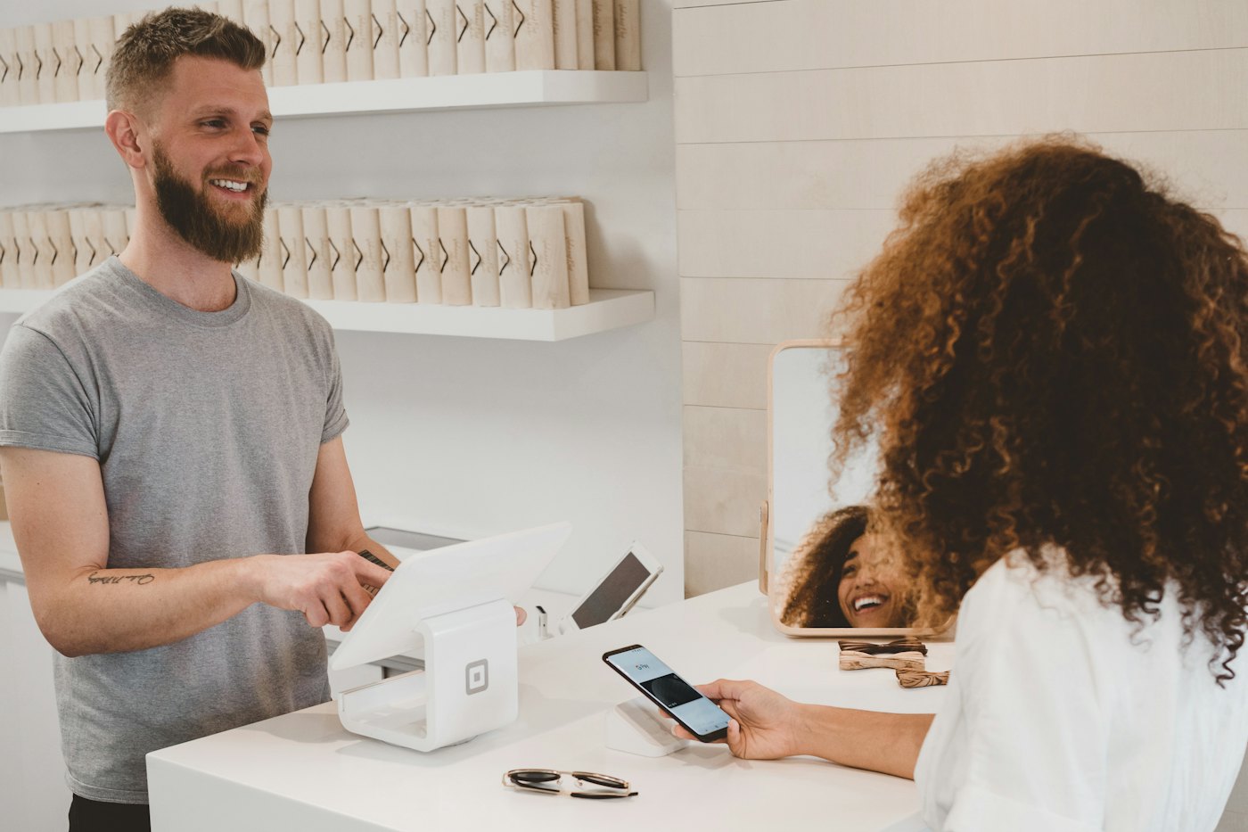 Atención en un mostrador, con el cliente mirando el celular al lado de la caja